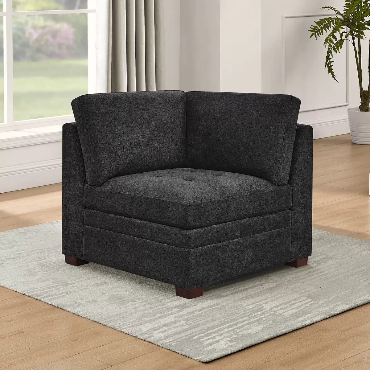 Front angled view of the Thomasville Tisdale dark grey fabric corner chair featuring tufted seat cushions and solid block wood legs on a modern light oak floor.
