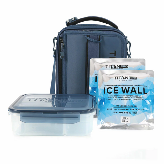Three-quarter view of the expandable blue Titan Pro Lunch Box in its expanded state on a stone kitchen island, with the bento box and ice walls placed neatly beside it.