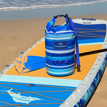 Vibrant tropical leaf print Tommy Bahama 20L TPU-coated waterproof dry bag with rolled buckle top and shoulder strap sitting on a wet wooden boat dock.