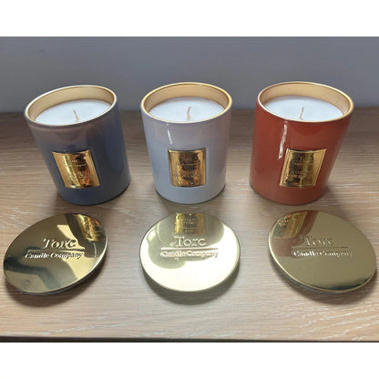 Three clear glass Torc scented candles with wooden lids arranged on a rustic wooden table displaying rich wax textures inside.