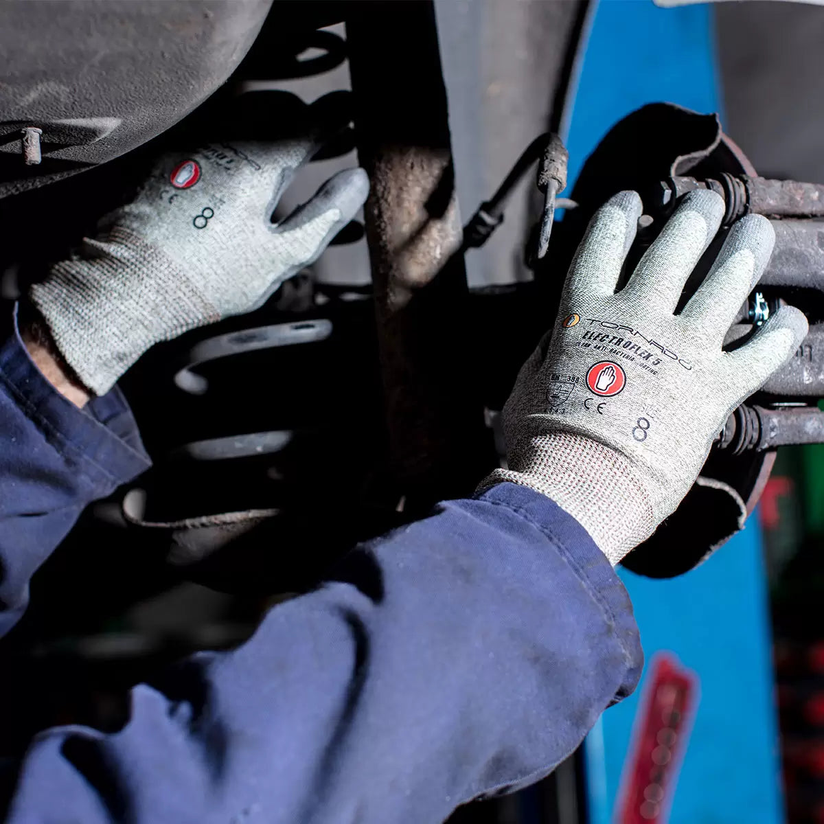 A bundle of twelve pairs of green and grey Tornado Electroflex 5 FTR safety gloves displaying the dark grey textured PU palm coating and the prominent thumb reinforcement patch.