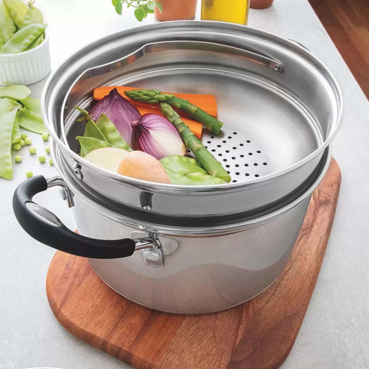A Tramontina 20cm stainless steel steamer set with a tempered glass lid, showcased on a clean kitchen induction hob.