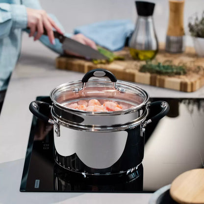 A Tramontina 20cm stainless steel steamer set with a tempered glass lid, showcased on a clean kitchen induction hob.