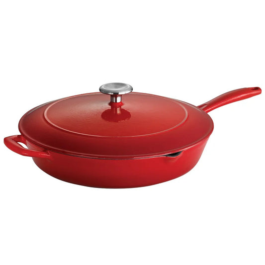 Vibrant red and blue enamelled cast iron 30cm saute pan with lid, matte black interior, side spouts, and silver lid knob resting on a kitchen table.