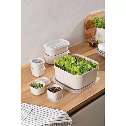 Tramontina 7-piece food storage set in cream and green, neatly organized on a kitchen counter.