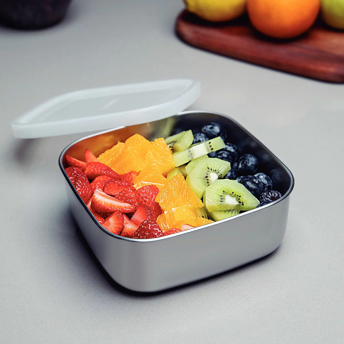 Tramontina 3-piece stainless steel food storage container set with airtight lids on a kitchen counter.