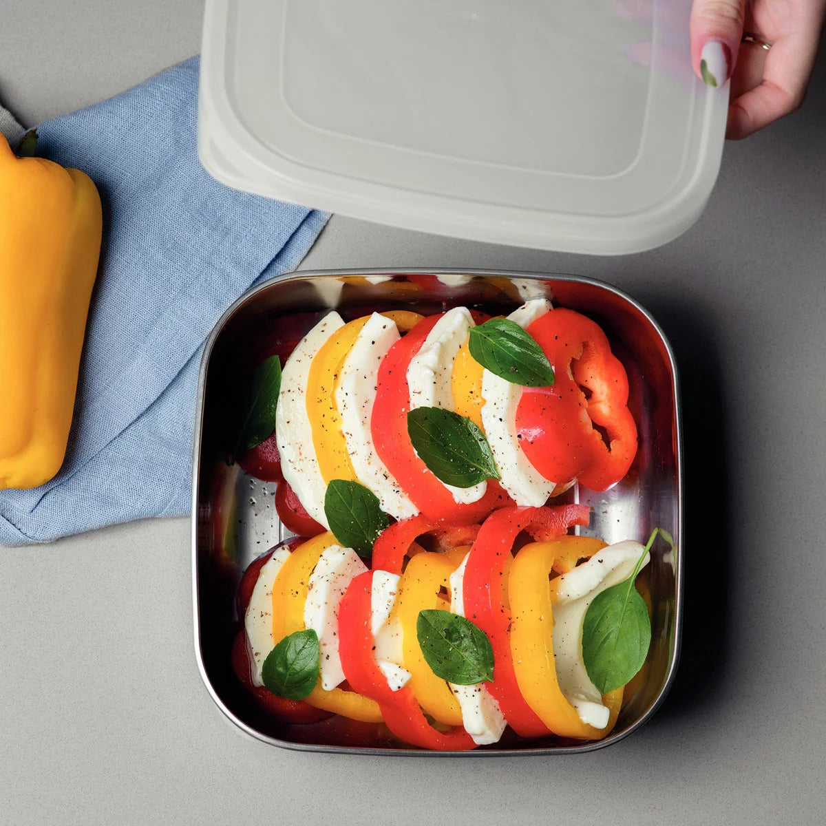 Tramontina 3-piece stainless steel food storage container set with airtight lids on a kitchen counter.