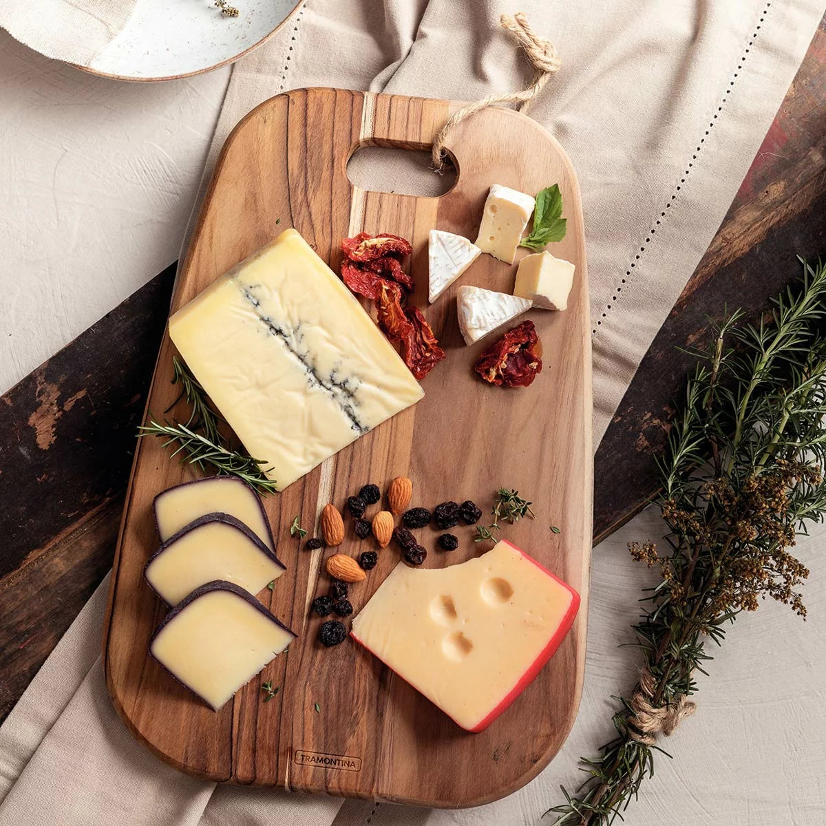 Two rich golden-brown Tramontina teak cutting boards of different sizes resting flat on a modern, brightly lit kitchen countertop.