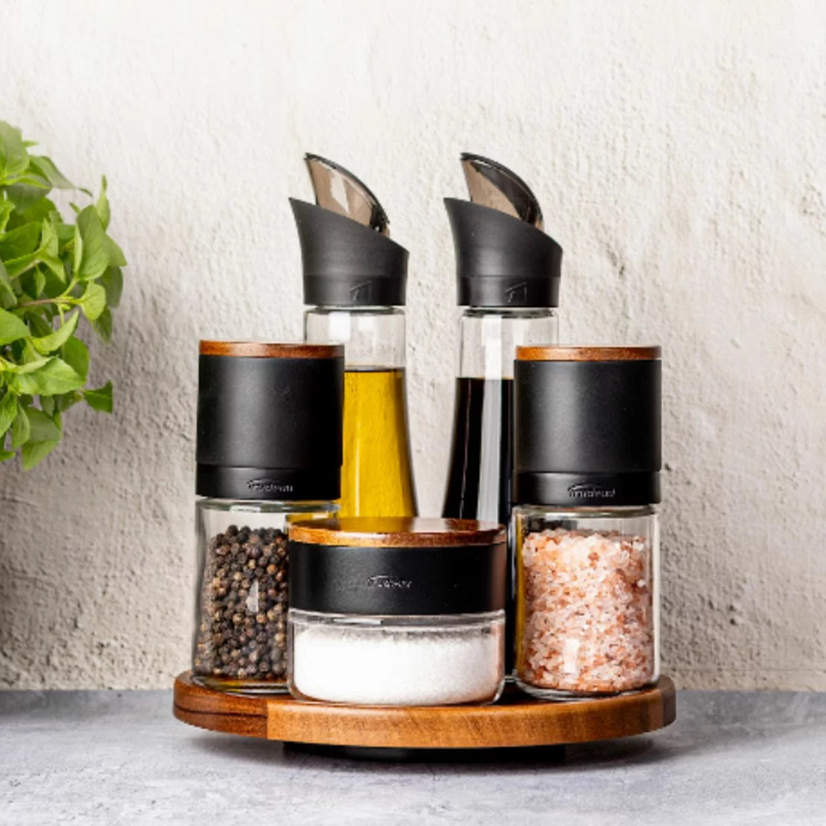 Trudeau 6-piece seasoning station featuring salt and pepper mills, oil bottles, and a rotating acacia base.