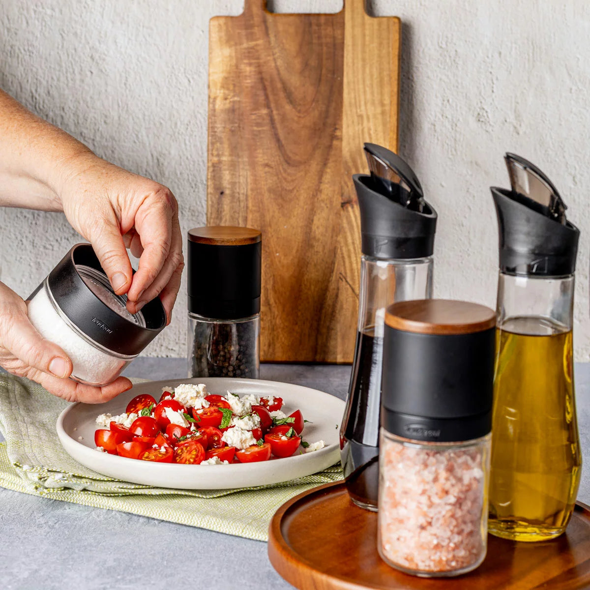 Trudeau 6-piece seasoning station featuring salt and pepper mills, oil bottles, and a rotating acacia base.
