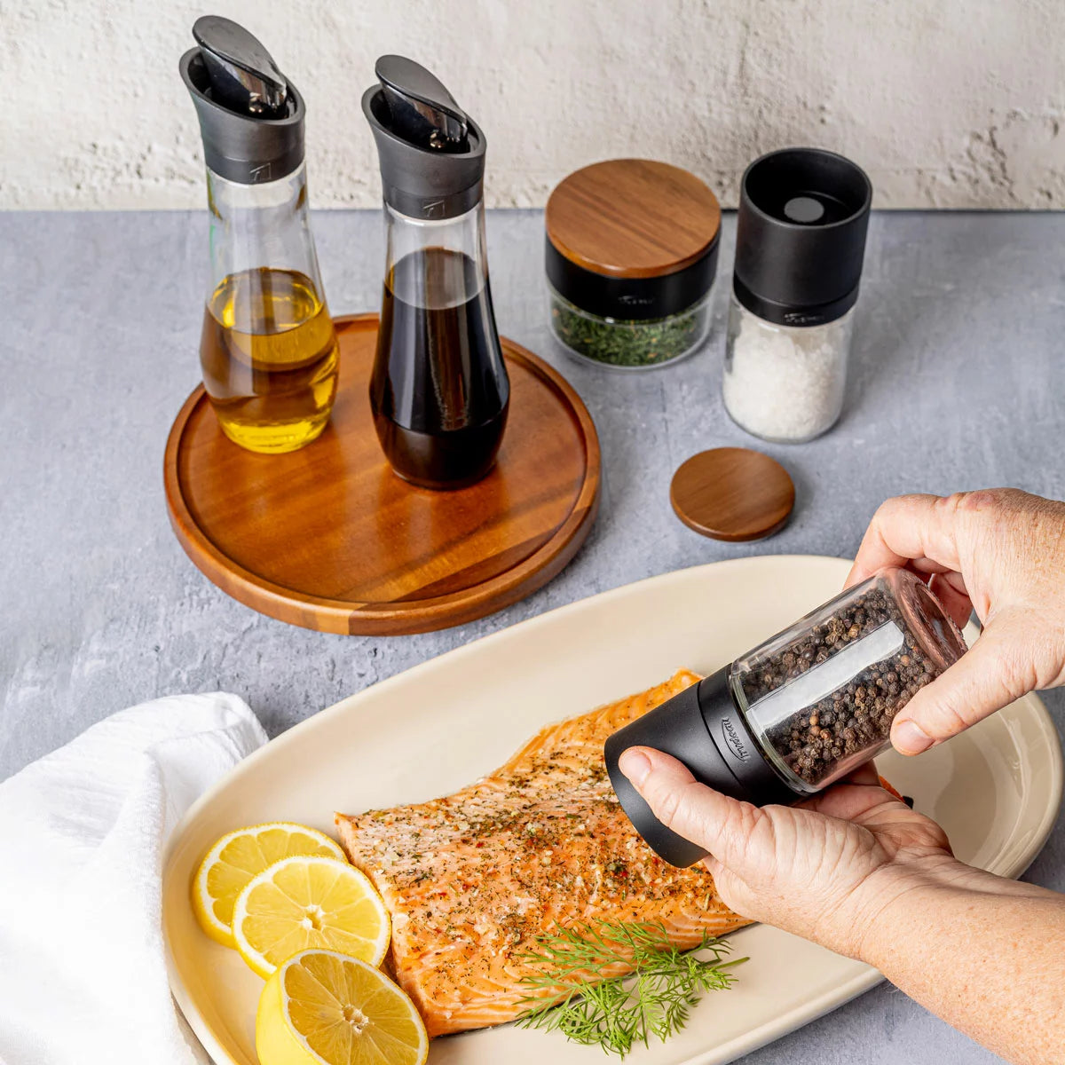Trudeau 6-piece seasoning station featuring salt and pepper mills, oil bottles, and a rotating acacia base.