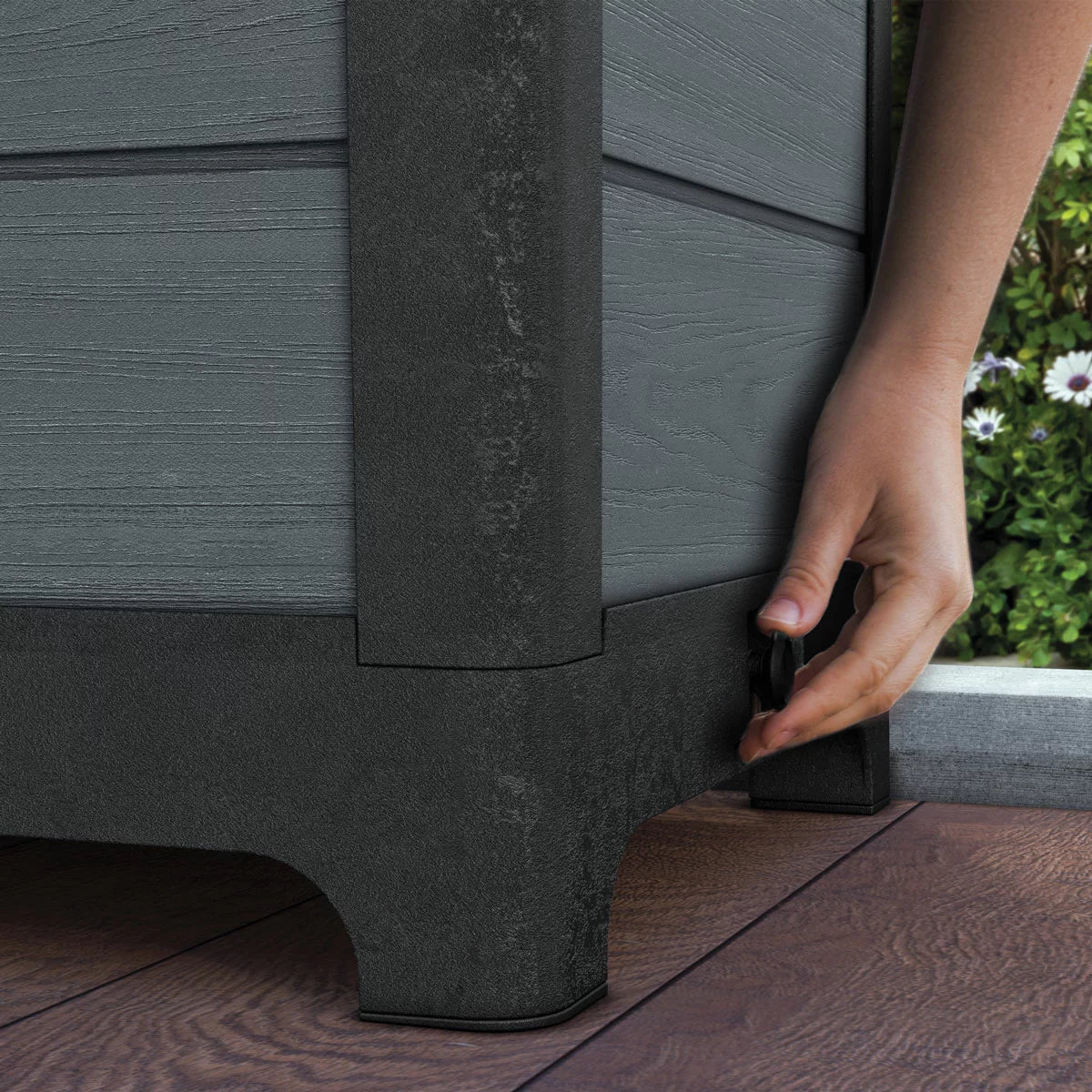 Front angle view of the Ashwood Brown and Grey Tulip Screen Planter with wood-grain texture and blooming plants on a stone patio.