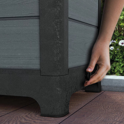 Front angle view of the Ashwood Brown and Grey Tulip Screen Planter with wood-grain texture and blooming plants on a stone patio.