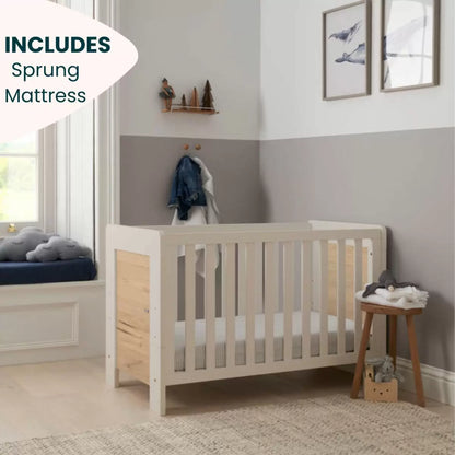 Three-quarter studio shot of the built white sand and distressed oak Tutti Bambini Alba Mini Cot Bed containing its fabric mattress.