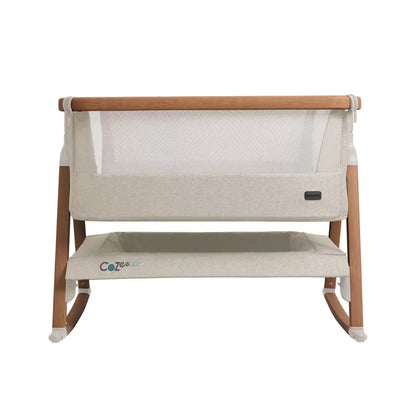 Tutti Bambini CoZee Air Bedside Rocking Crib in Walnut frame and Ecru fabric set up beside a adult bed with mesh side lowered.