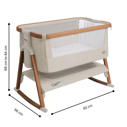 Tutti Bambini CoZee Air Bedside Rocking Crib in Walnut frame and Ecru fabric set up beside a adult bed with mesh side lowered.