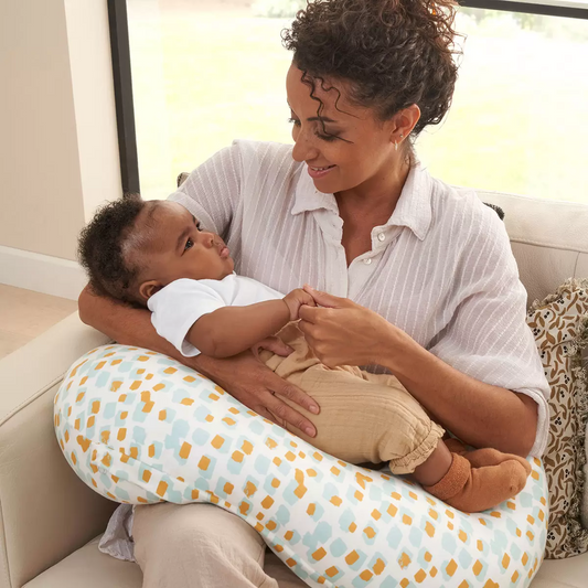 Soft bamboo-cotton Tutti Bambini Run Wild pattern feeding pillow resting on a nursery chair in an arched ergonomic shape.