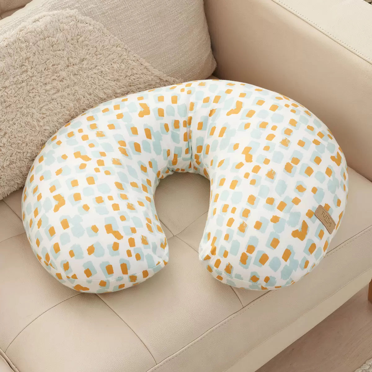Soft bamboo-cotton Tutti Bambini Run Wild pattern feeding pillow resting on a nursery chair in an arched ergonomic shape.