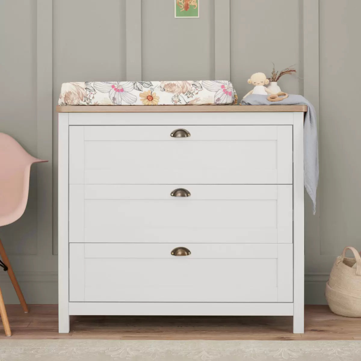 Front view of the white and oak Tutti Bambini Verona changing unit chest with three drawers and traditional brass handles shot in a brightly lit room.