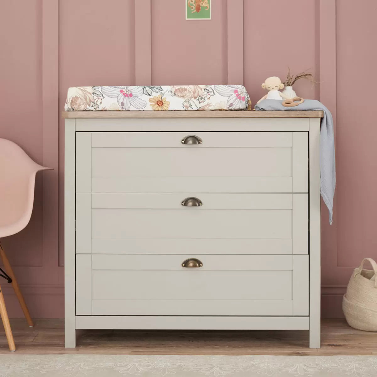 Front view of the grey and oak Tutti Bambini Verona changing unit featuring three closed drawers with traditional brass handles in a bright nursery setting.
