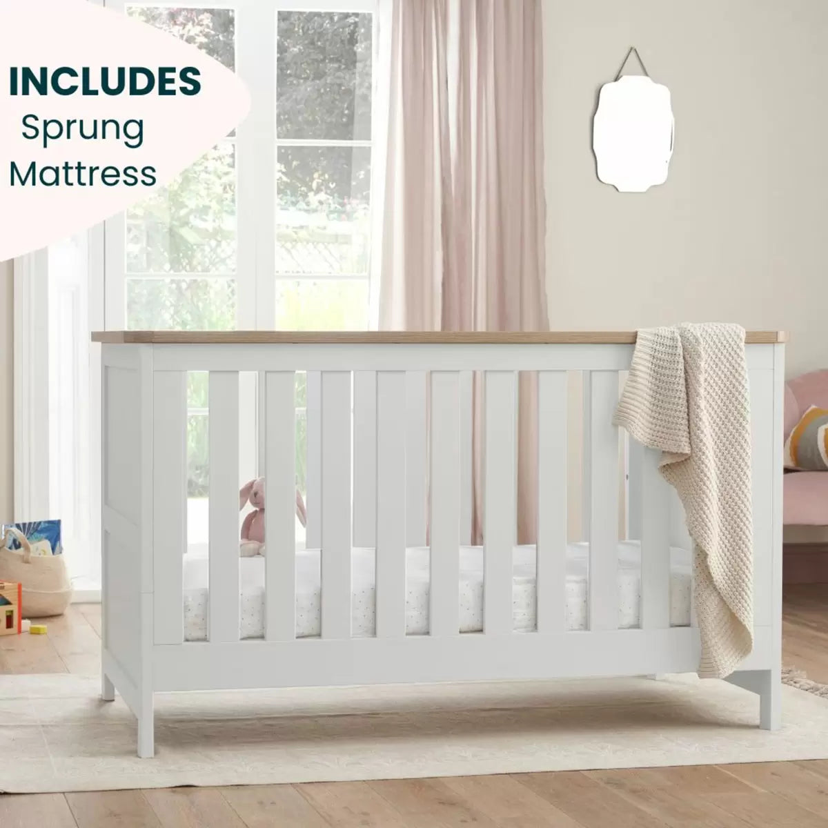 Three-quarter view of the built white and oak Tutti Bambini Verona cot bed showing the mattress inside a clean minimalist bedroom setting.