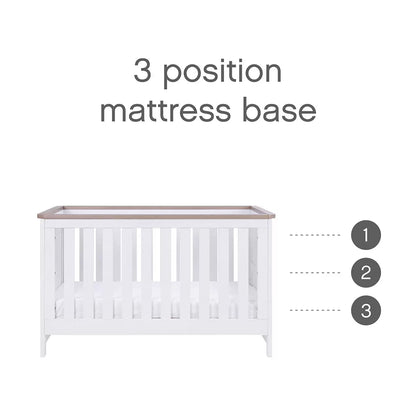 Three-quarter view of the built white and oak Tutti Bambini Verona cot bed showing the mattress inside a clean minimalist bedroom setting.