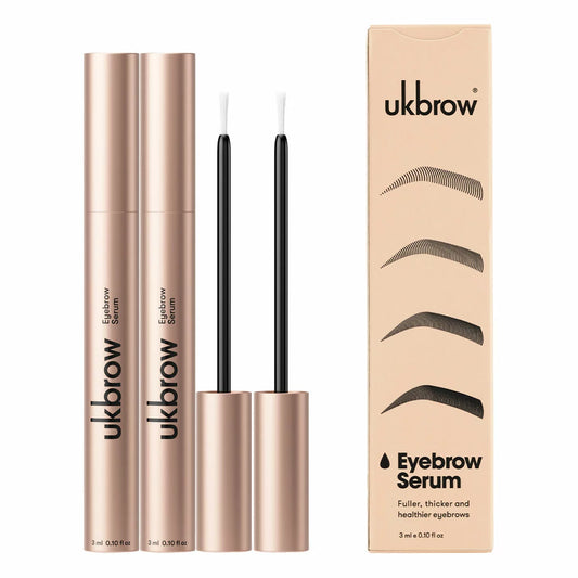 Two sleek tubes of UK Brow Eyebrow Serum with a precision applicator wand resting gently on a polished marble vanity top.