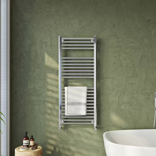 Front view of the chrome-finished Ultraheat Chelmsford towel radiator measuring 1172x500mm mounted on a contemporary dark tiled bathroom wall holding a folded white towel.