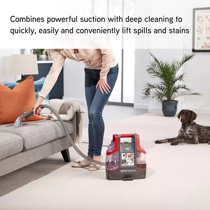 Blue and grey VAX Corded Spot Washer CDCW-CSXD sitting on a living room floor beside its multi-purpose cleaning attachments and solution bottle.