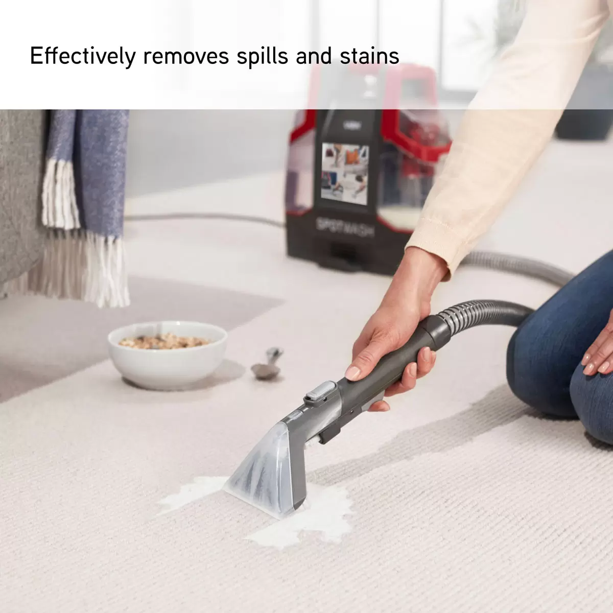 Blue and grey VAX Corded Spot Washer CDCW-CSXD sitting on a living room floor beside its multi-purpose cleaning attachments and solution bottle.