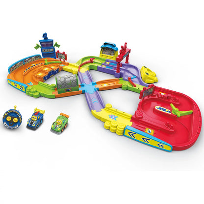 Brightly colored VTech Toot-Toot Drivers Super Circuit RC Raceway plastic track layout featuring a red RC car, motorized racer, tunnel, and remote control on a light wood floor.
