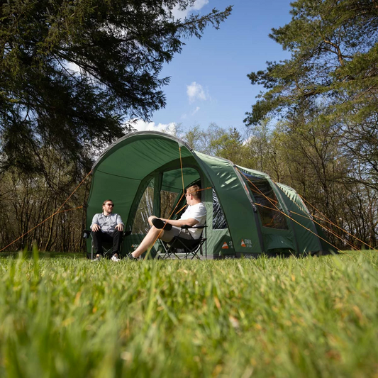 dark green Vango Staffa Air 500 inflatable 5-person tent pitched on a grassy campsite at dusk, highlighting its spacious front canopy area and smooth, rigid AirBeam support structure.