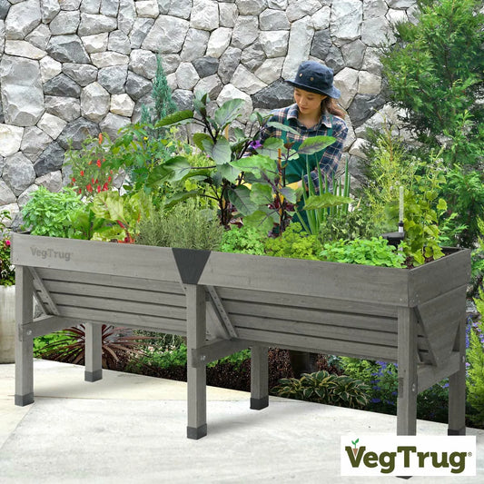 A stylish 1.8m grey wooden VegTrug Classic raised bed standing on a patio filled with various green vegetable plants.