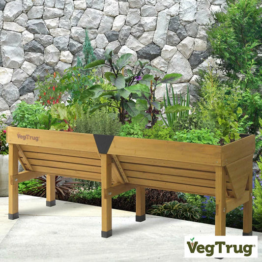 A 1.8m natural wood VegTrug Classic raised bed filled with growing vegetables on a paved patio.