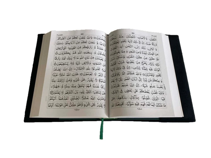 Angle view of a black soft velvet covered 13-line Quran with gold Arabic logo next to its matching velvet holder inside an open presentation gift box.