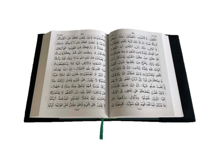 Angle view of a black soft velvet covered 13-line Quran with gold Arabic logo next to its matching velvet holder inside an open presentation gift box.