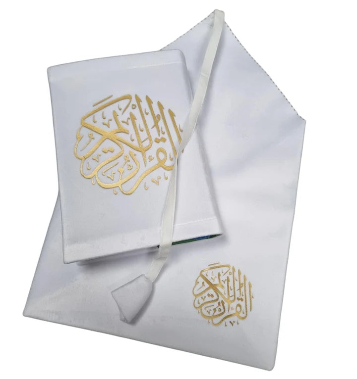 Angle view of a black soft velvet covered 13-line Quran with gold Arabic logo next to its matching velvet holder inside an open presentation gift box.