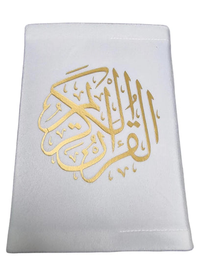 Angle view of a black soft velvet covered 13-line Quran with gold Arabic logo next to its matching velvet holder inside an open presentation gift box.