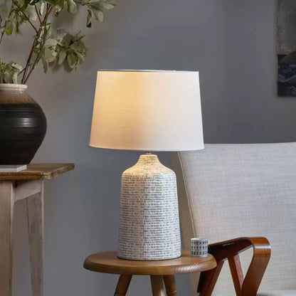 Front view of the Vondra ceramic table lamp showing its abstract hand-glazed grey and white ceramic base and textured ivory linen shade on a light oak bedside table.