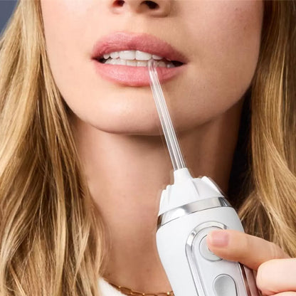 Two Waterpik Cordless Plus water flossers in white, presented alongside a collection of specialized cleaning tips and grey travel bags on a minimalist bathroom shelf.