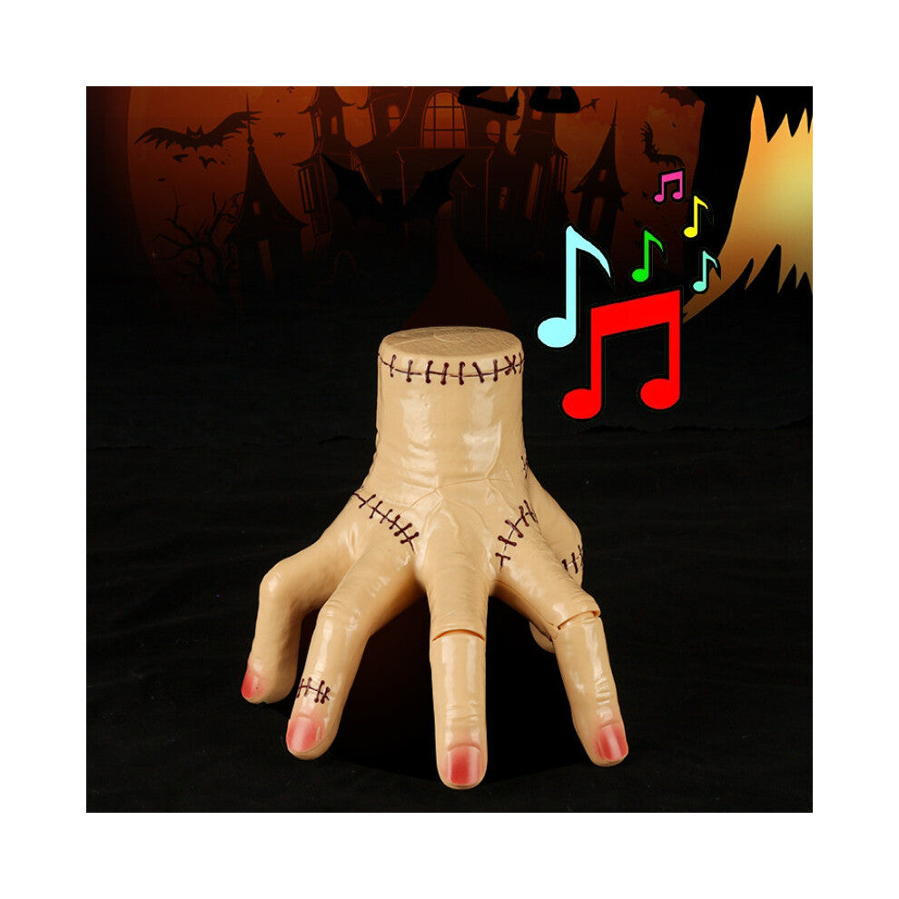 An animated Wednesday Addams Thing crawling hand prop featuring LED lights and spooky details positioned on a dark table.