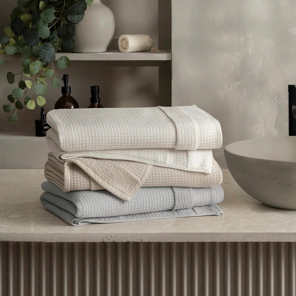 Close-up shot of the Welhome 100% cotton waffle-textured towel in grey, showing the terry backing on a modern bathroom wooden shelf.
