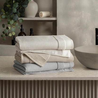 Close-up shot of the Welhome 100% cotton waffle-textured towel in grey, showing the terry backing on a modern bathroom wooden shelf.