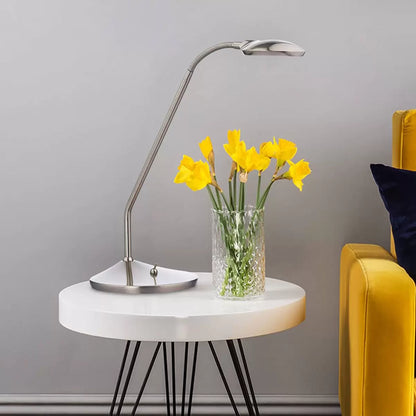 A modern Wellington satin chrome LED task table lamp with an adjustable neck bent forward on a clean wooden desk, showcasing its bright 3000K light beam.