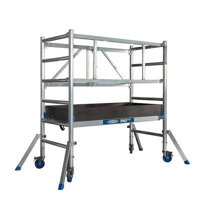 A silver aluminium Werner PROPLUS folding scaffold tower base pack with black swivel castors, a platform deck featuring an integrated trapdoor, and protective wooden toe boards set against a plain backdrop.
