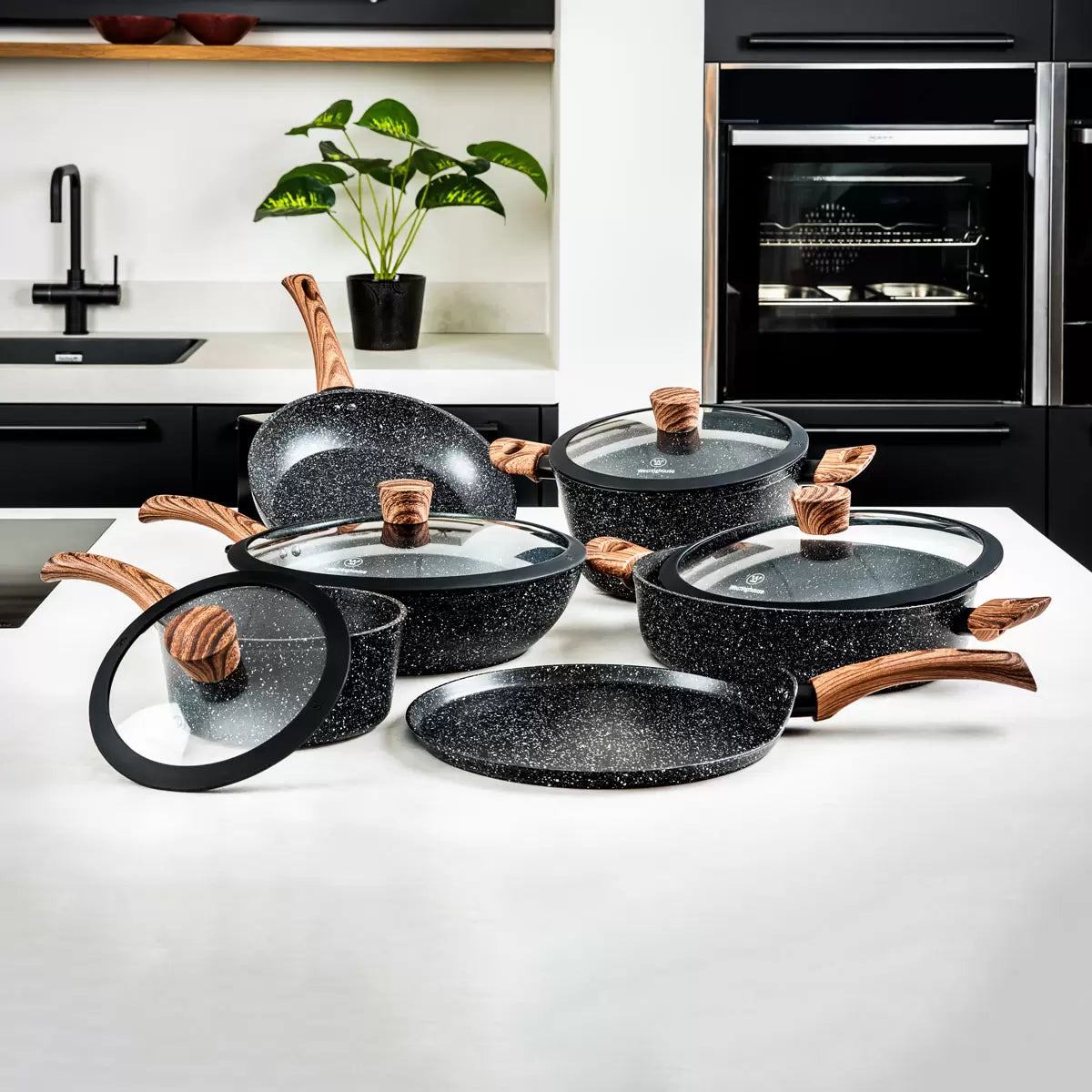 Westinghouse Special Edition 11-piece non-stick cookware set featuring speckled black finish with wood effect handles, including pans, pots, and glass lids displayed on white kitchen counter
