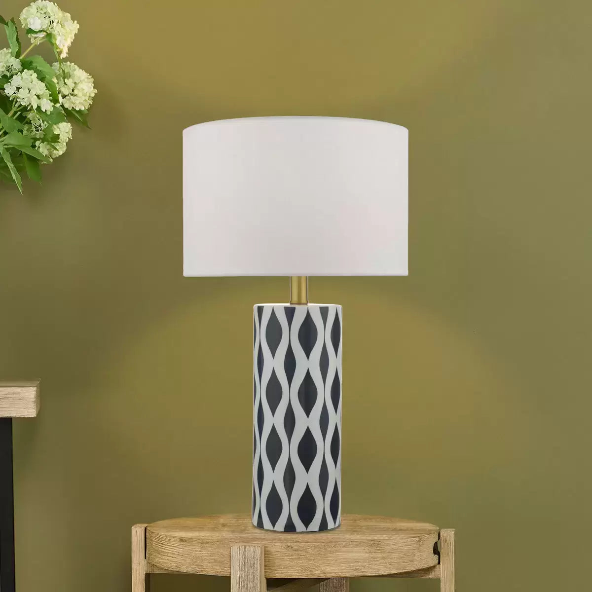 Front view of the Weylin table lamp featuring a glossy blue and white glazed ceramic base under a crisp white faux silk shade, illuminating a modern wooden bedside table.