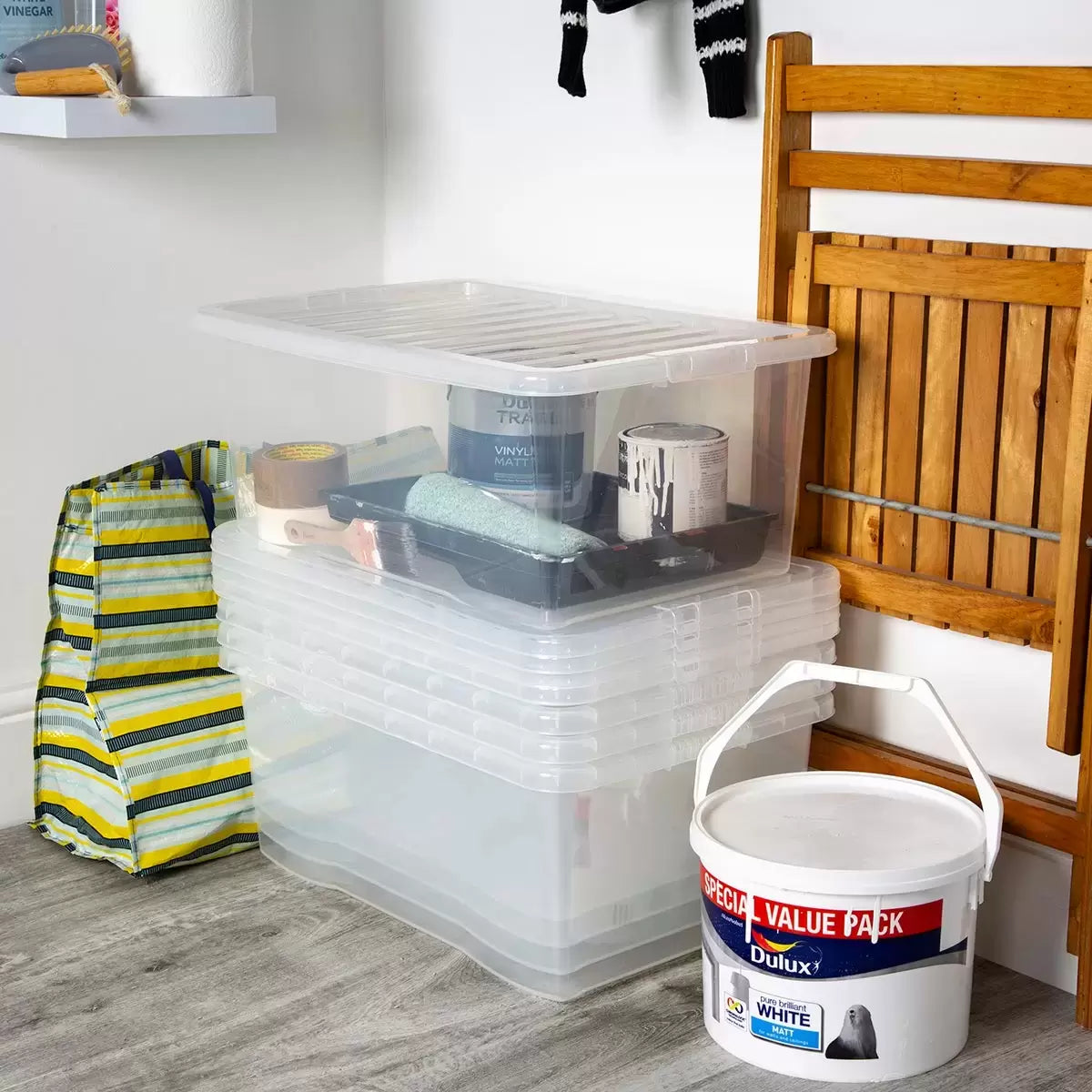 Five stacked Wham 45-litre crystal clear plastic storage boxes with matching clip-on lids arranged neatly in a bright, modern home utility room.
