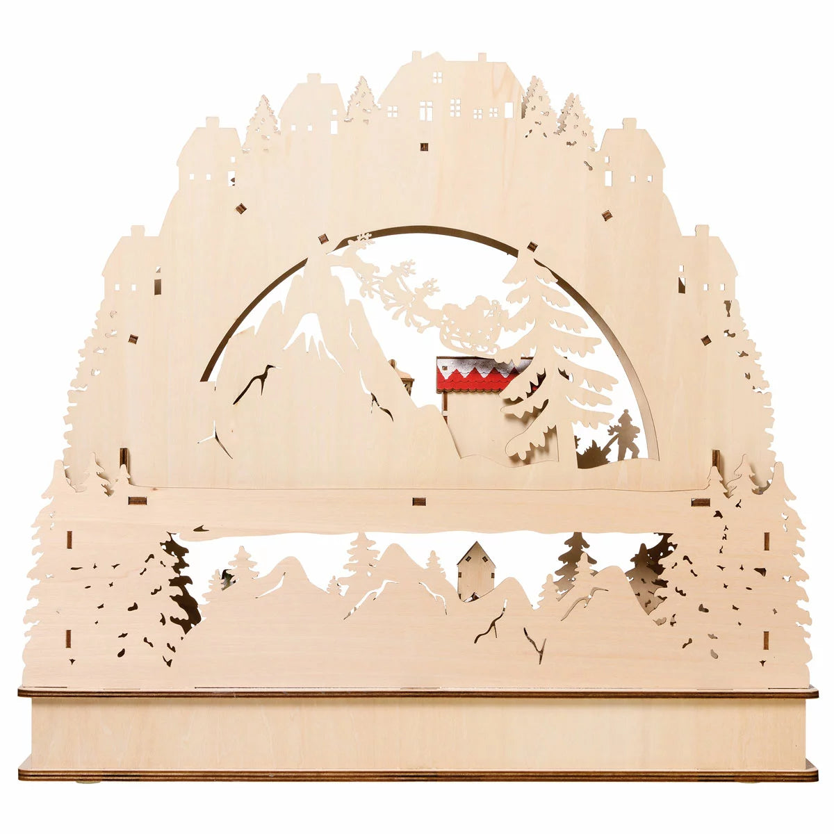 Front view of a laser-cut wooden alpine village advent calendar illuminated by warm internal LED lights on a wooden table.