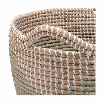 Pair of two nesting handwoven natural brown seagrass storage baskets with integrated handles arranged on a light wood floor in a brightly lit living room.